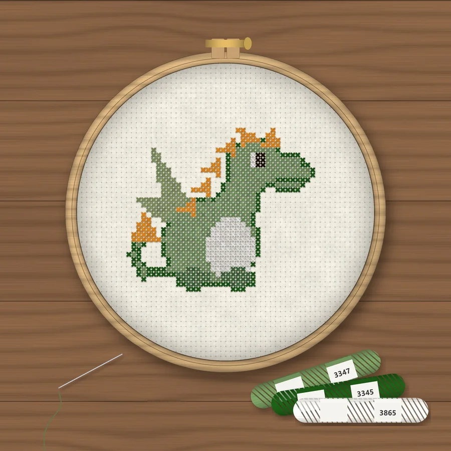 Baby Dragon cross stitch finished in a wooden embroidery hoop with DMC thread skeins