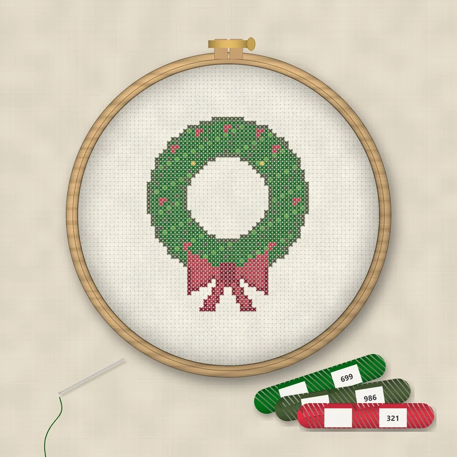 Christmas Wreath cross stitch finished in a wooden embroidery hoop with DMC thread skeins