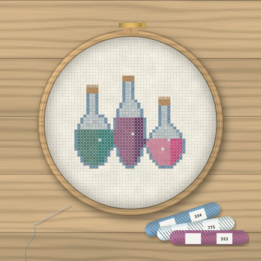 Magic Potions cross stitch finished in a wooden embroidery hoop with DMC thread skeins