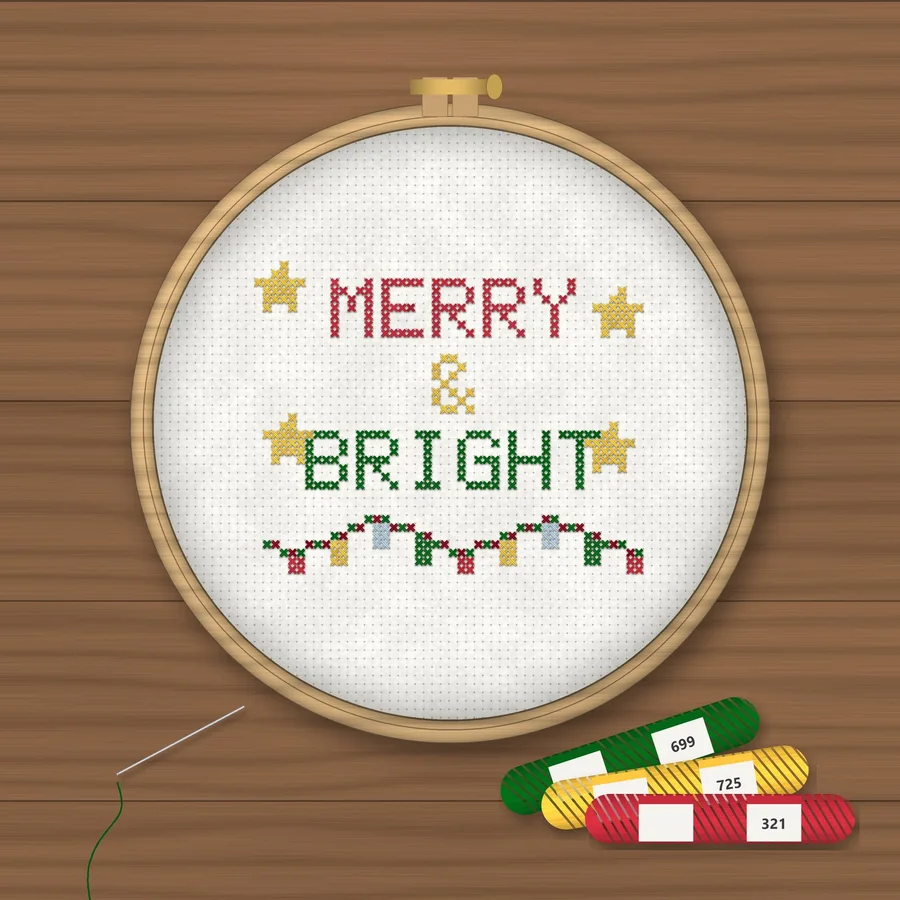 Merry and Bright cross stitch finished in a wooden embroidery hoop with DMC thread skeins