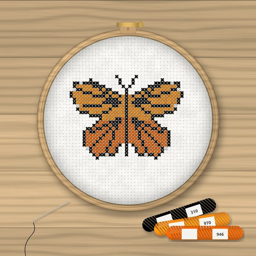 Monarch Butterfly cross stitch finished in a wooden embroidery hoop with DMC thread skeins