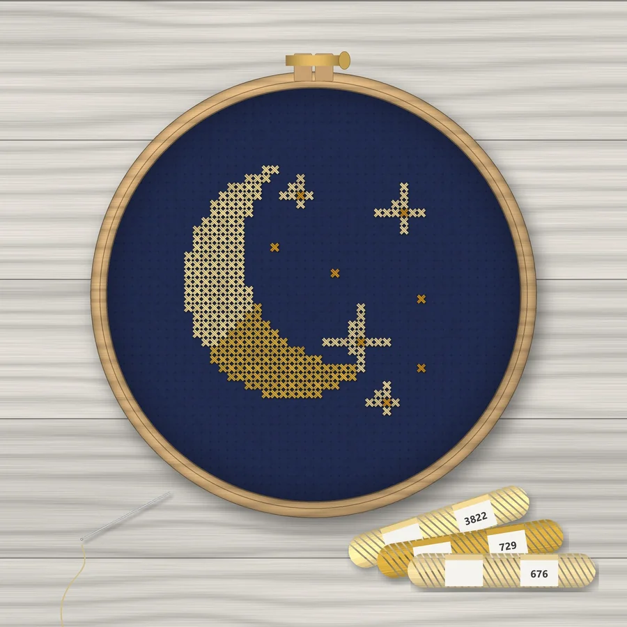 Moon and Stars cross stitch finished in a wooden embroidery hoop with DMC thread skeins