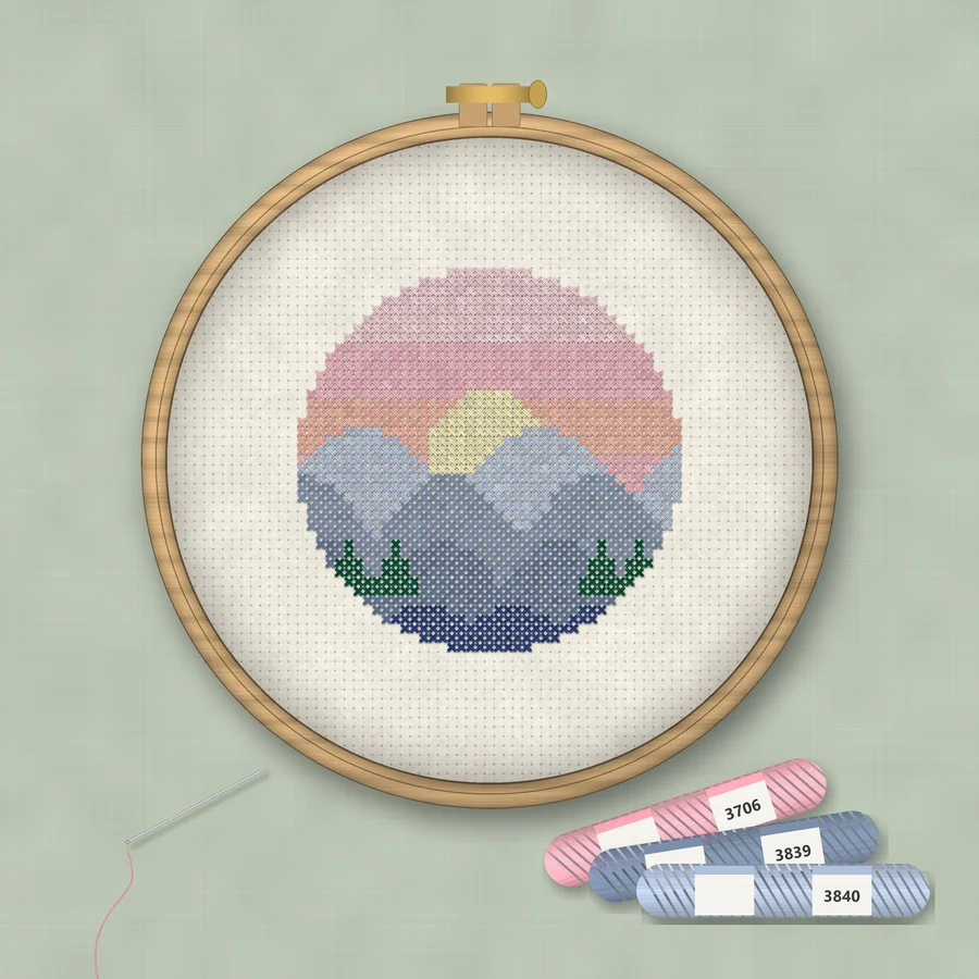 Mountain Sunset cross stitch finished in a wooden embroidery hoop with DMC thread skeins