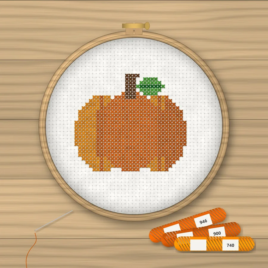 Pumpkin cross stitch finished in a wooden embroidery hoop with DMC thread skeins