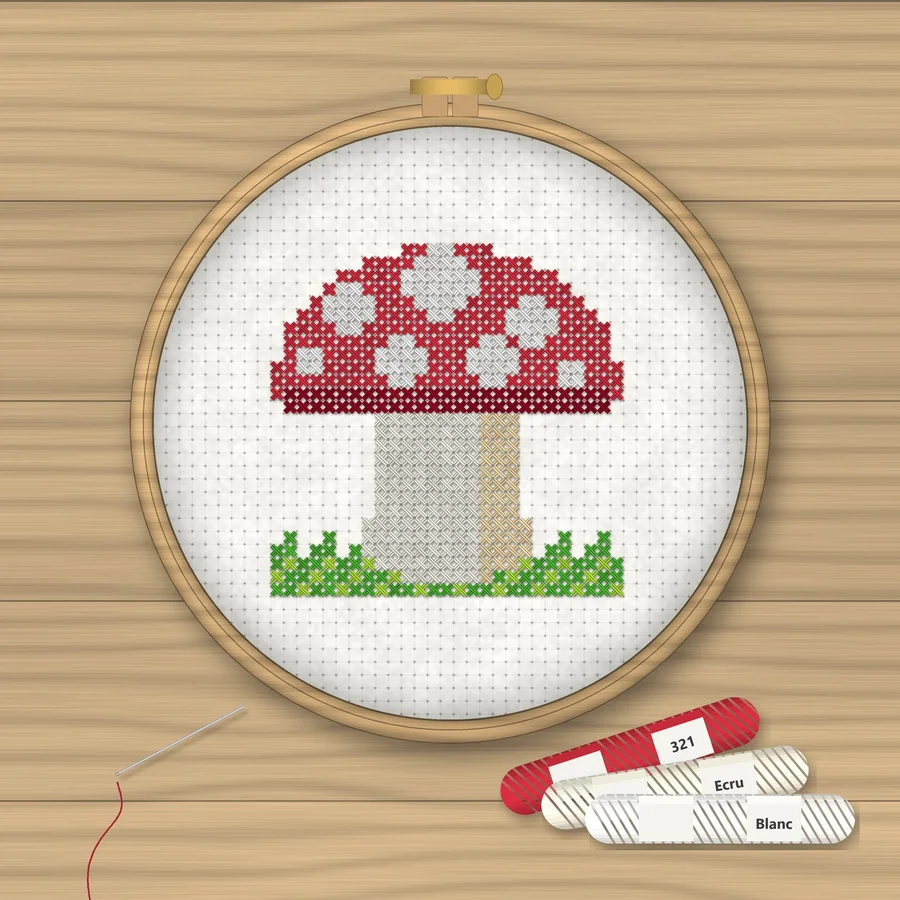Red Mushroom cross stitch finished in a wooden embroidery hoop with DMC thread skeins