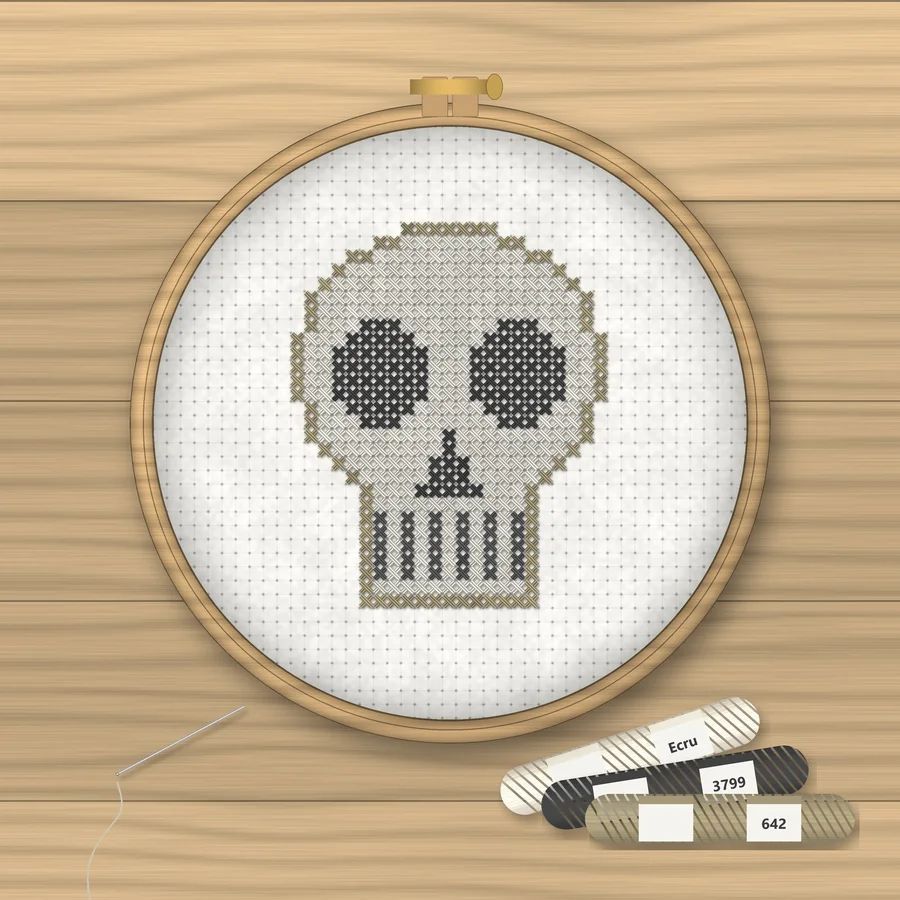 Skull cross stitch finished in a wooden embroidery hoop with DMC thread skeins