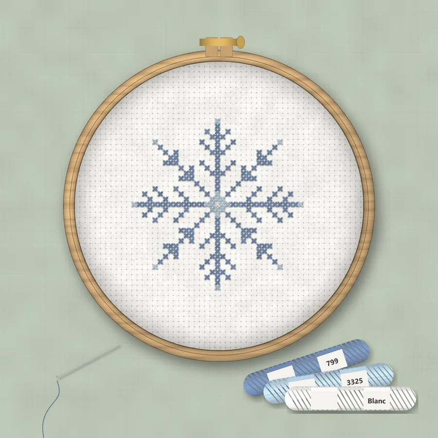 Snowflake cross stitch finished in a wooden embroidery hoop with DMC thread skeins