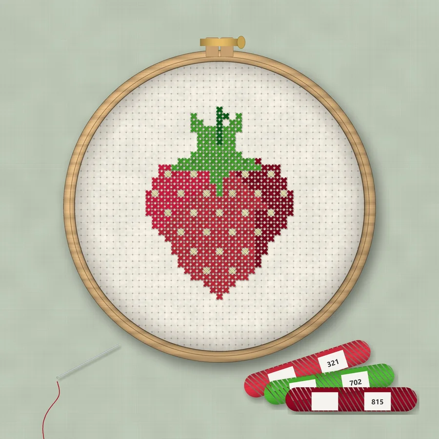 Strawberry cross stitch finished in a wooden embroidery hoop with DMC thread skeins