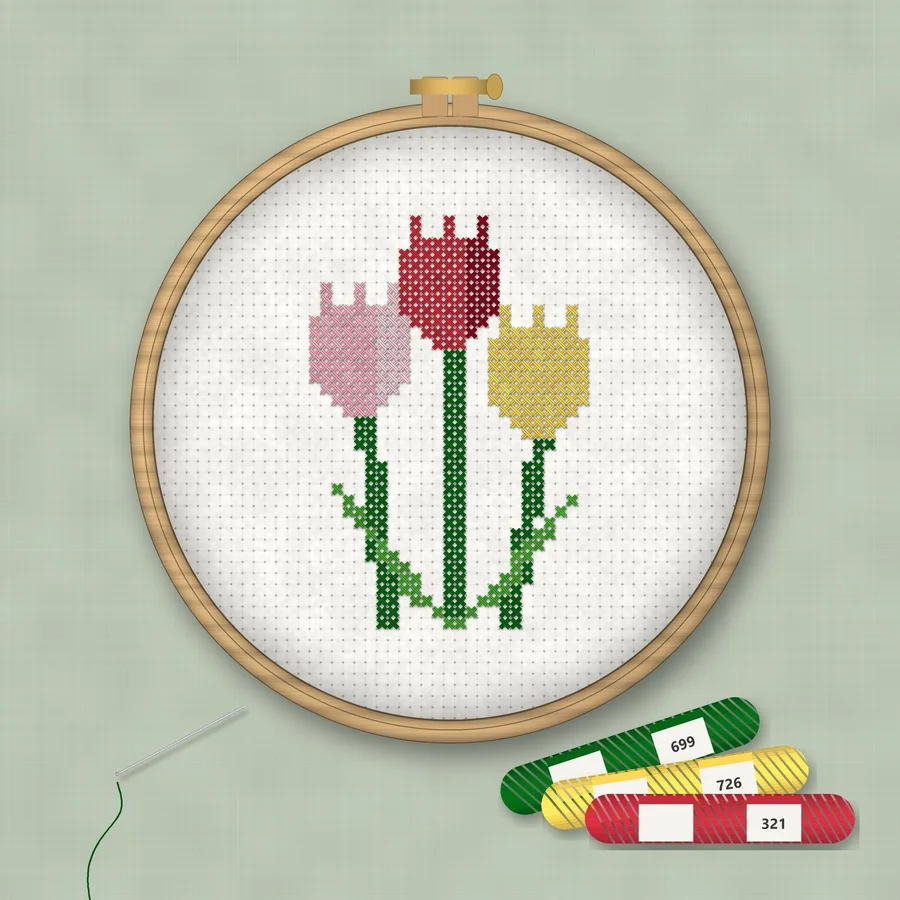 Tulips cross stitch finished in a wooden embroidery hoop with DMC thread skeins